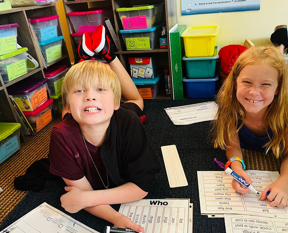 Elementary students working on phonics worksheets in a bright classroom